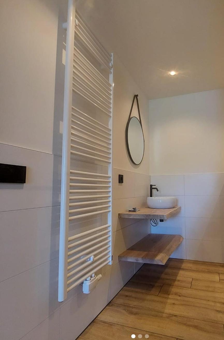 Badkamer met handdoekradiator en wastafel op een houten blad