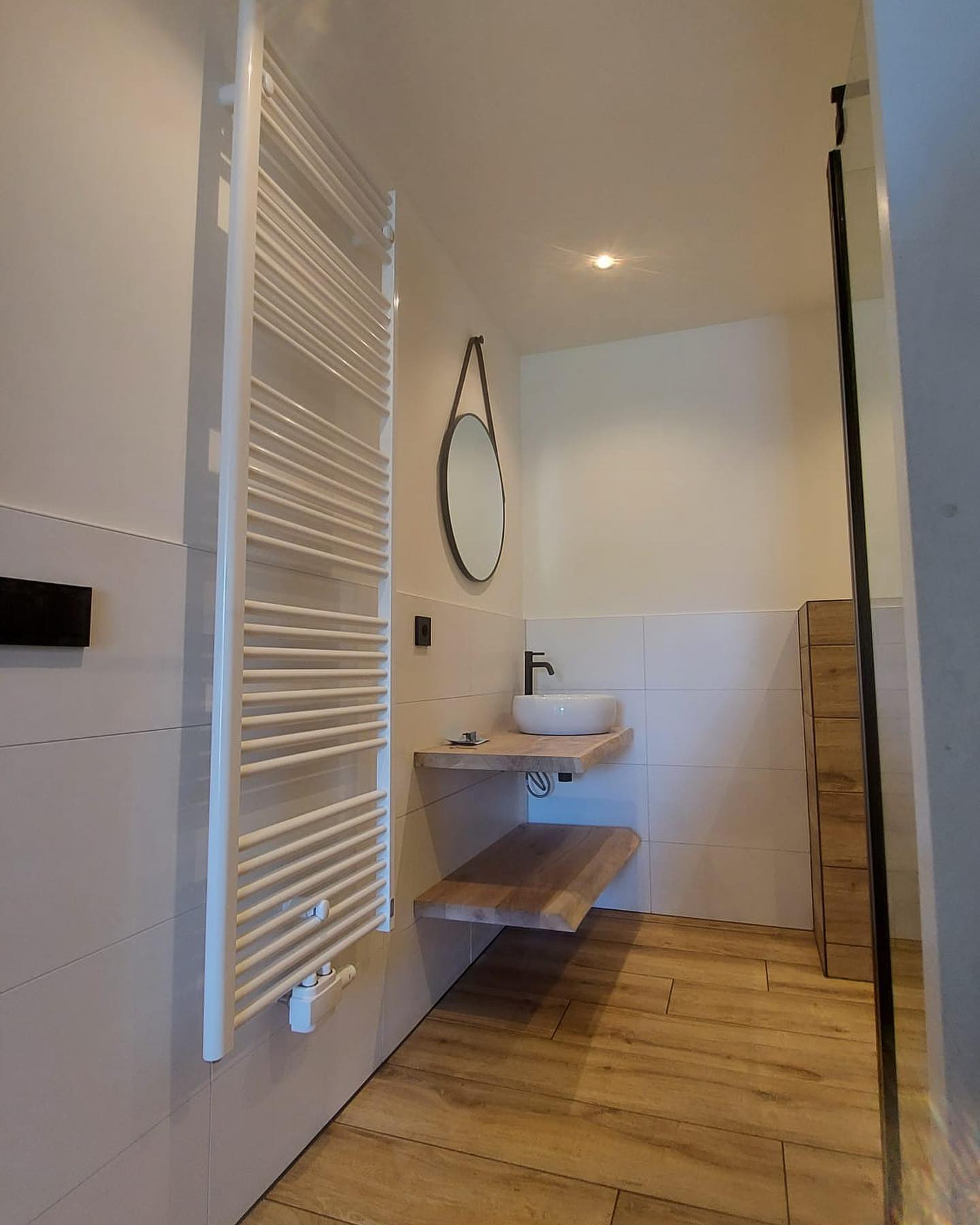 Gerenoveerde badkamer met zwevende wastafel en ronde spiegel